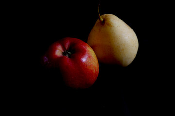 close up of apple and pear in isolated on the dark background