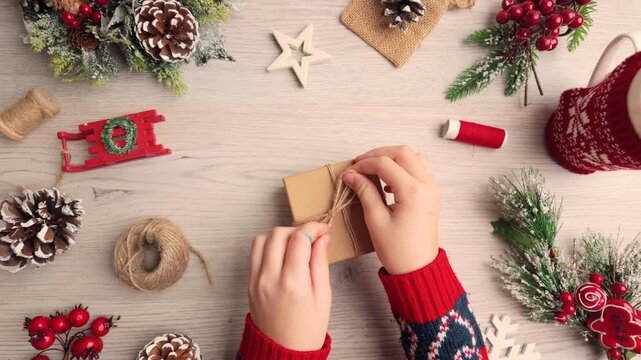 Slow motion horizontal shot of hands tying twine on a small gift box during a simple DIY holiday wrapping tutorial