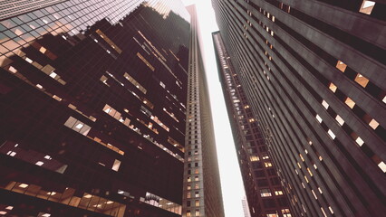 Tall buildings tower high, their glass facades reflecting the fading light of dusk. The scene captures the essence of city life, with windows glowing in warm hues.