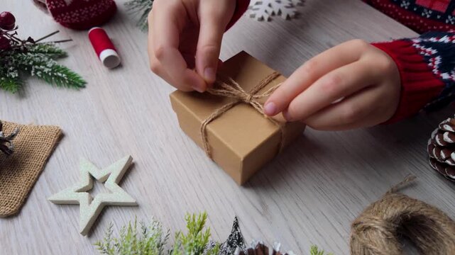 Detailed normal-speed shot of hands tightening twine on a small gift box during a holiday wrapping process