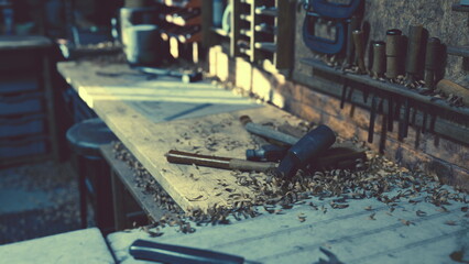 Sunlight streams into a serene workshop, illuminating a wooden workbench scattered with wood shavings and various tools. The air is filled with a sense of craftsmanship and creativity.
