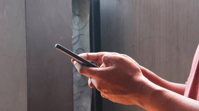 Asian man is typing on a smartphone secretly in the corner