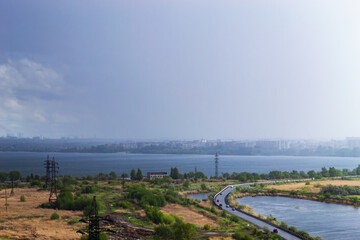 Rainstorm over lake and industrial cityscape