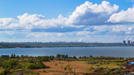 Power plant by lake under bright beautiful clouds