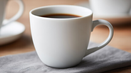 Blank white ceramic mug filled with black coffee on a soft gray cloth.