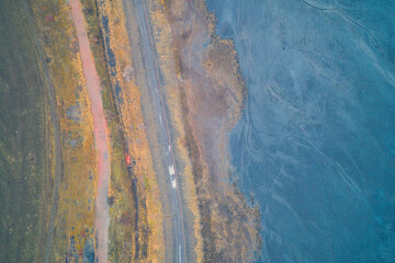 Obraz premium Drone aerial shot capturing an abstract texture of an industrial landscape. Strong contrast between warm, earthy tones of dirt gravel old road and cool blue and grey colors of sludge toxic waste area