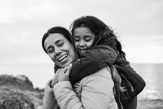 Happy latin mother and daughter having fun together during winter time - Family and love concept - Focus on faces - Black and white editing