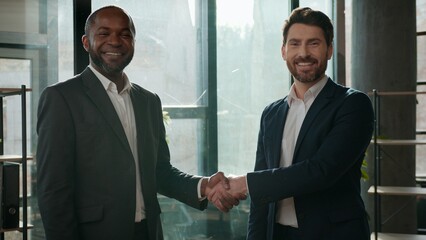 Two diverse positive multiracial businessmen business team men handshaking meeting satisfied hiring job welcome office formal agreement colleagues handshake Caucasian African American managers work