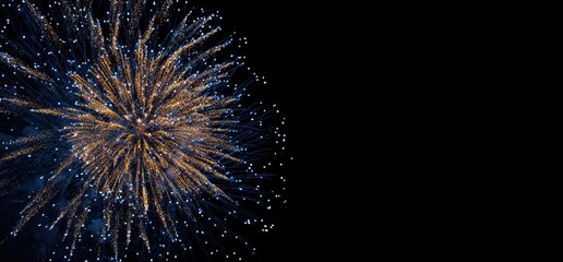 An eye-catching display of fireworks in vibrant gold and blue against a solid black background