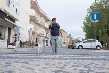Father and Daughter Crossing the Street While He Holds Her Hand and Looks Around