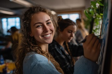 Smiling young woman painting on canvas in a bright art classroom, surrounded by other students working creatively, expressing joy, concentration, and artistic passion in a relaxed learning environment