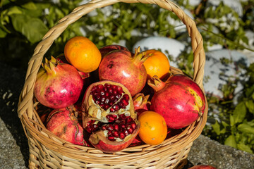 Side view of basket with pomegranates, one cut open