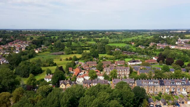 Aerial drone footage of the village of Ripon in North Yorkshire in the UK showing the historic British village and streets full of rows of terrace houses from above on a sunny day in the summer time