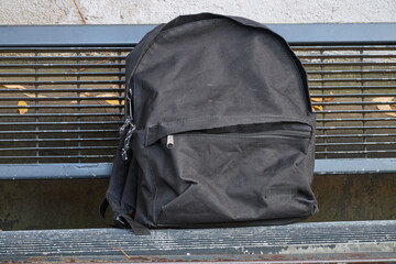 Well used black backbag on metal bench