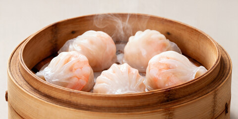 Steaming hot shrimp dumplings delicately arranged in a traditional bamboo steamer basket, a delicious Asian delicacy ready to be savored.