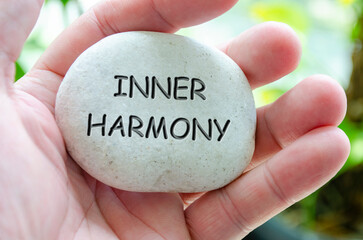 Inner Harmony text engraved on white dark stone with hand holding it. Life harmony concept.