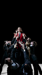 Leader in red coat elevated above group as symbolic model for leadership training and team education. Concept of guidance, coaching, role modeling, teamwork development and professional growth.