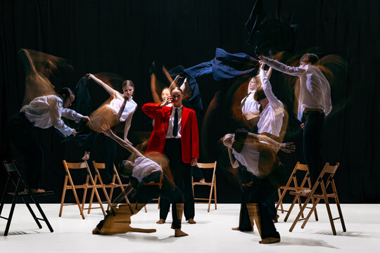 Ensemble with motion-blur performing expressive movements around still central figure in red jacket. Concept of emotional theatre, expressive movement language, dynamics and artistic storytelling.