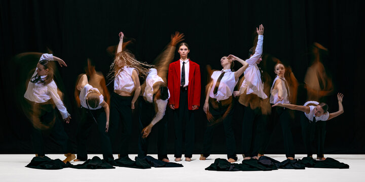 Leader standing still in red jacket while team moves chaotically around her in motion blur. Concept of organizational dynamics, behavioral imbalance, adaptation and group tension, calm versus chaos.