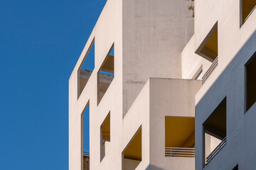 Modern architecture housing in Montpellier France showcasing geometric facade openings, warm palette, dynamic shadows and bright daylight