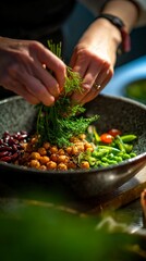 Hands delicately add fresh herbs to a colorful bowl of chickpeas, greens, and beans, highlighting culinary creativity and the beauty of healthy eating in vibrant cuisine.