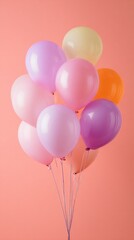 Colorful balloons in various pastel shades float gracefully against a soft peach background, creating a playful and cheerful atmosphere perfect for celebrations or decoration.