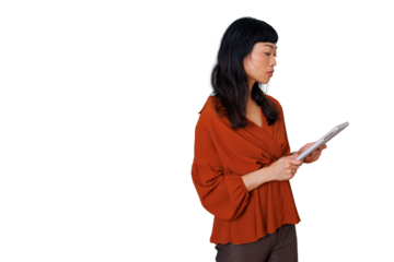 Asian professional woman intently reading content on a digital tablet, standing against a transparent background