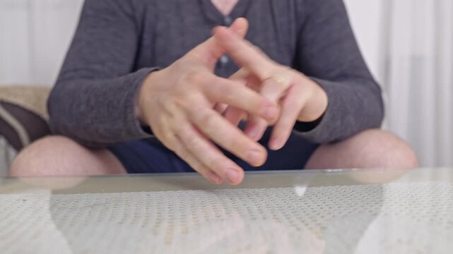 A close-up shot of a person's hands as they crack their knuckles repeatedly, showcasing a common habit that can be associated with stress, nervousness, or contemplation.