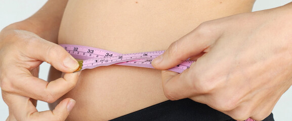 Woman Measuring Her Waist With a Pink Tape Measure
