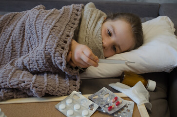 A little girl is lying in bed sick. The concept of illness, cold, acute respiratory viral infection