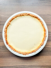 Freshly made cheesecake sits in ceramic baking dish viewed from above, showing smooth creamy surface and simple homemade look