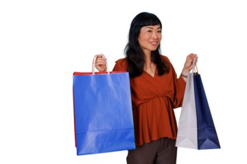Asian woman smiling and holding shopping bags enjoying a successful retail experience on a transparent background