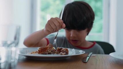 Parent helping child cut fried food at home during lunch, showing supportive hands guiding fork and knife over plate in calm family setting