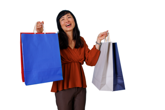 Happy asian woman shopping and laughing, carrying many colorful shopping bags, celebrating consumerism and retail joy
