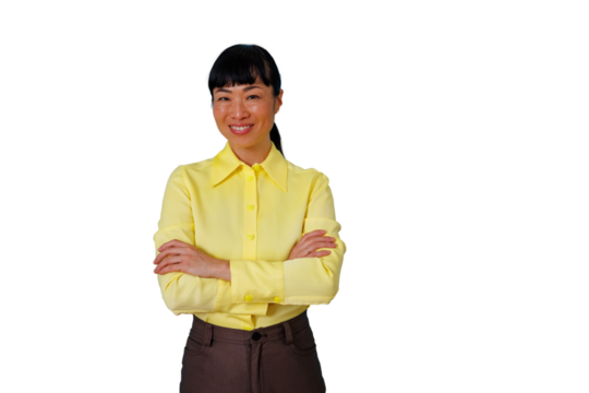 Confident asian businesswoman smiling at camera, standing with arms crossed, dressed in yellow shirt, symbolizing professional success