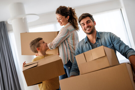 Smiling man and woman enjoy unpacking with child moving to own home. Rent, mortgage concept