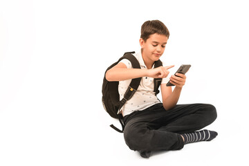 Teenage boy with backpack sits cross-legged, using smartphone, isolated on white background. Suitable for education, technology, youth, and digital lifestyle concepts.