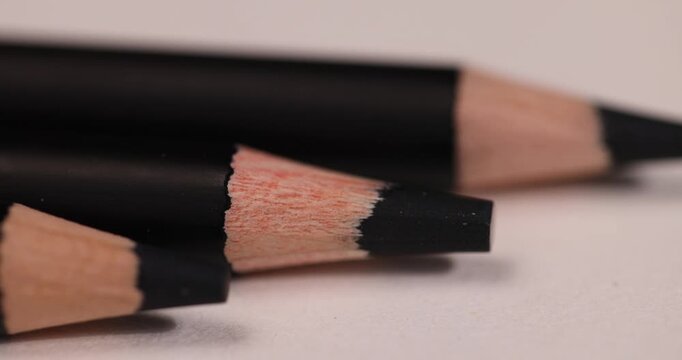 a row of black pencils folded on cheap loose paper, wooden pencils with graphite lead for drawing or other work