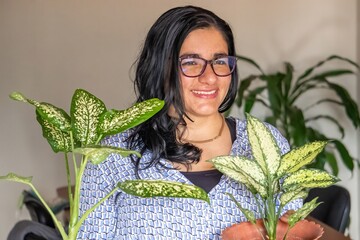 A woman is holding two plants, one of which is a fern