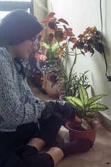 A woman is kneeling down in front of a plant, tending to it