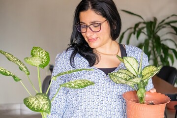 A woman is holding a plant in a pot and smiling