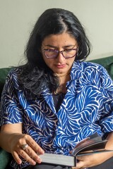 A woman wearing glasses is reading a book