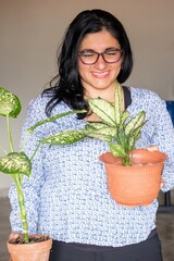 A woman is holding two plants, one of which is a small potted plant