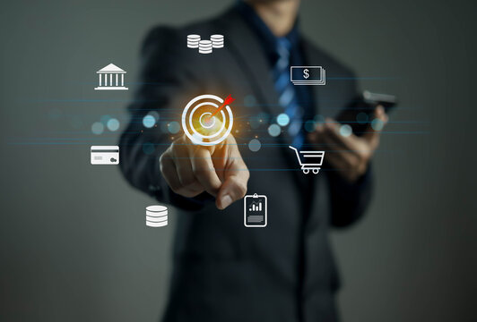 Businessman using digital technology to achieve financial goals, touching virtual target icons for online marketing, data analytics, e-commerce, and fintech innovation in modern business strategy.