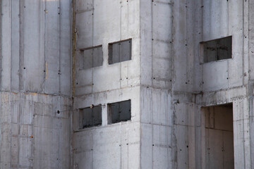 Exterior of Concrete Wall Frame of Building under Construction. Architectural origin of Structure. Monolithic box with holes for windows and floor slabs on sunny day at Construction Site.