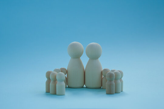 Group of wooden man. large and small figures on a blue background. family, community, business, psychology.