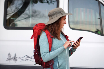 Sports and outdoor activities for women over 40. Woman ready to go trekking, looking at the app on her phone.
