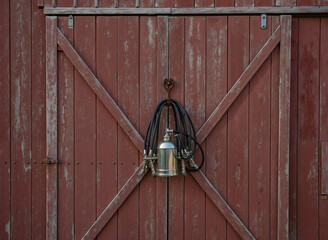 Vintage  milking machine hangs on a red barn door.