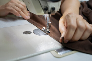 Tailor sews a brown evening dress in her workshop stock photo