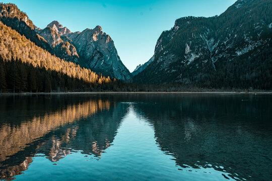 Fototapeta View of majestic mountains reflected in the tranquil lake waters, framed by lush forests under a clear sky, Auronzo di Cadore, Province of Belluno, Italy.
